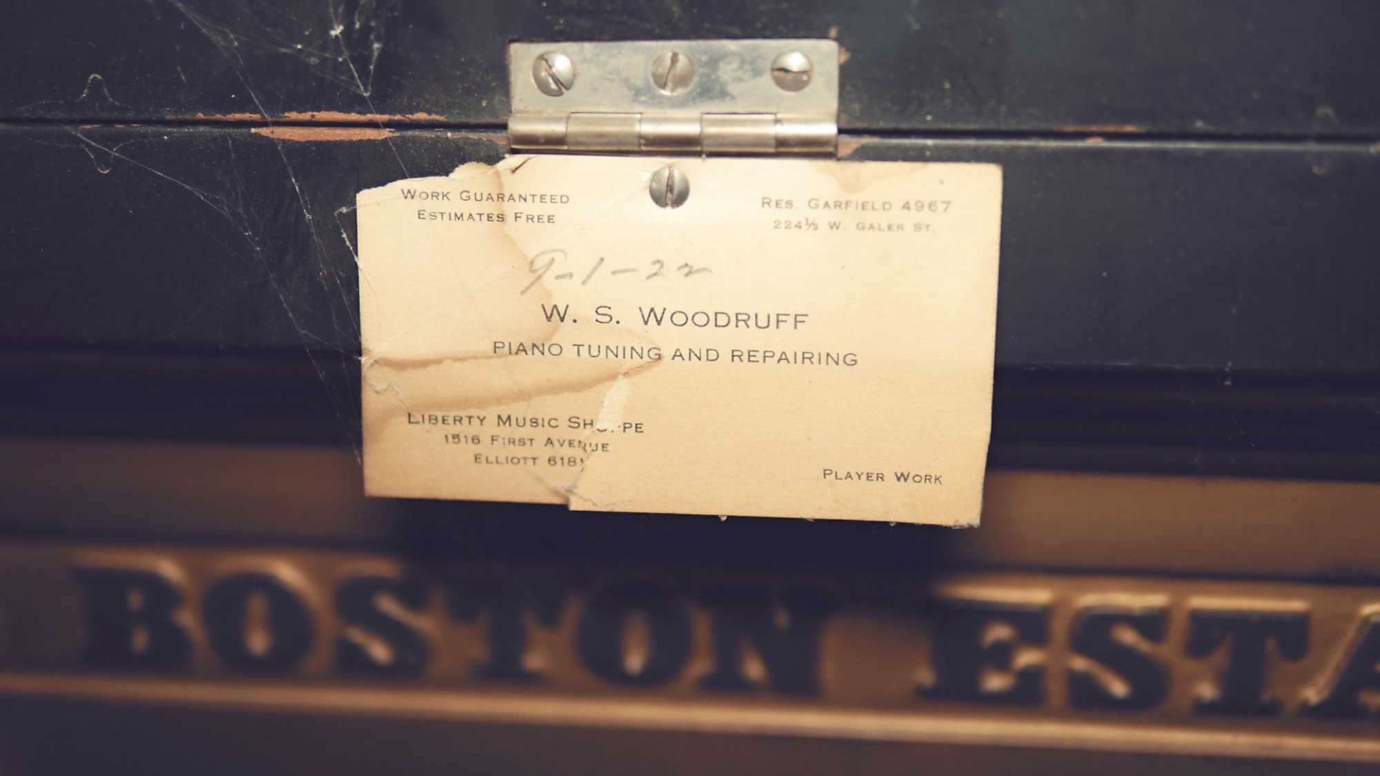 A piano tuner's card from 1922 stapled to the inside of piano.